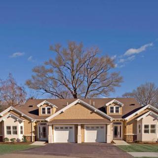 A suburban townhouse or duplex with a shared driveway and garages.