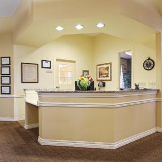 A welcoming reception area with a desk, flowers, and framed pictures on the walls.