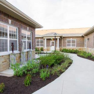 A brick building with a landscaped garden and a curved concrete pathway.