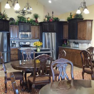 A cozy kitchen and dining area featuring wooden furniture, stainless steel appliances, and decorative plants.