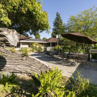 A sunny garden patio with outdoor furniture and lush greenery.