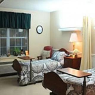 A cozy room with two beds, a window, and a lamp.