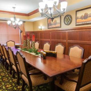 A beautifully arranged dining room featuring a long wooden table, elegant upholstery, and decorative elements.
