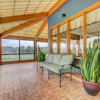 A spacious sunroom with large windows, featuring a comfortable bench and potted plants.