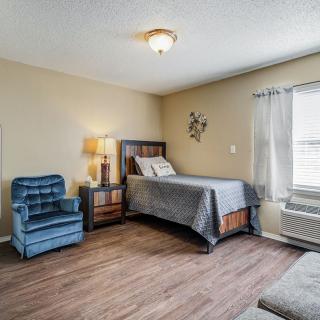 A cozy bedroom with a bed, armchair, and wooden flooring.