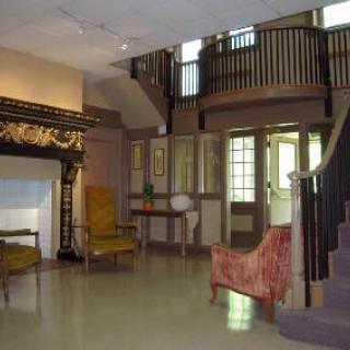 A spacious living room featuring a fireplace, comfortable seating, and a staircase leading to an upper balcony.