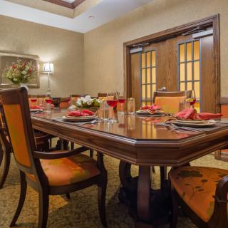A well-set formal dining room with a polished wooden table and cushioned chairs.