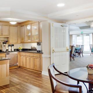 A modern kitchen with wooden cabinets opens into a spacious dining area, featuring hardwood floors and abundant natural light.