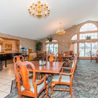A spacious dining room with elegant wooden furniture and chandeliers, featuring large windows that let in natural light.