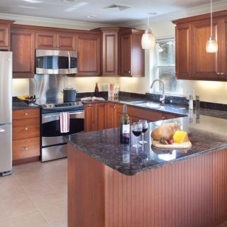A modern kitchen with wood cabinets, stainless steel appliances, and a granite countertop island.