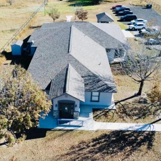 Aerial view of a large building with a parking lot and surrounding trees.