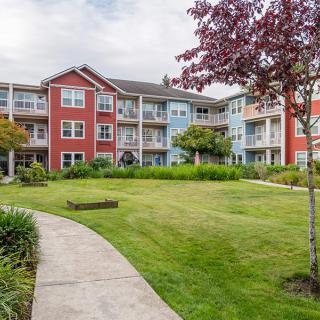 A well-maintained apartment building with a landscaped lawn and walkway.