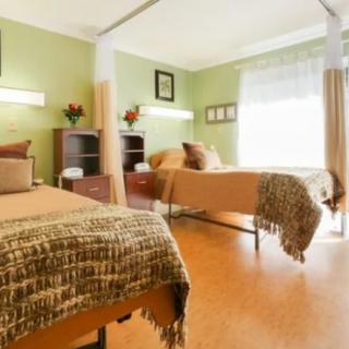A cozy bedroom with two neatly made beds, soft lighting, and large windows.