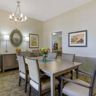 A modern dining room with elegant decor, featuring a chandelier and stylish wall art.