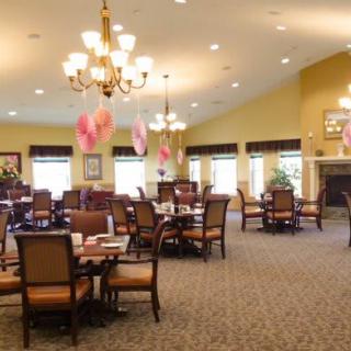A spacious dining room with elegant chandeliers and neatly arranged tables and chairs.