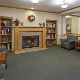 A cozy library space featuring a fireplace surrounded by bookshelves and comfortable seating.