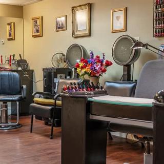 A cozy salon interior featuring chairs, hair dryers, and a vibrant flower arrangement.