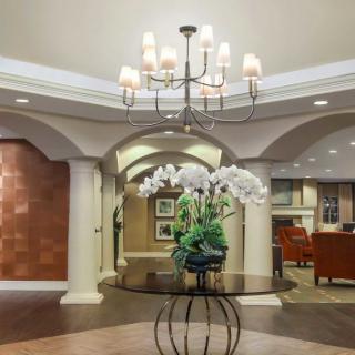 A well-decorated lobby featuring a central table with flowers and a chandelier.