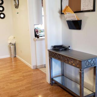 A home hallway with a wooden floor, featuring a decorative table and wall-mounted mail holder.