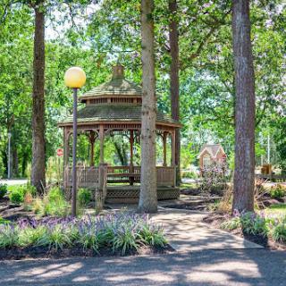 A serene park scene featuring a gazebo surrounded by lush greenery and trees.