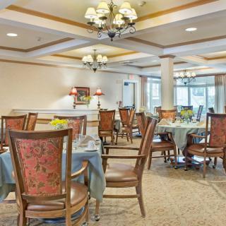 Elegant dining room setting with chandeliers and neatly arranged tables and chairs.