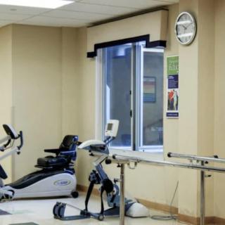 A room with fitness equipment including stationary bikes and rehabilitation tools.
