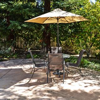 A serene garden patio with an umbrella and furniture set for relaxing.