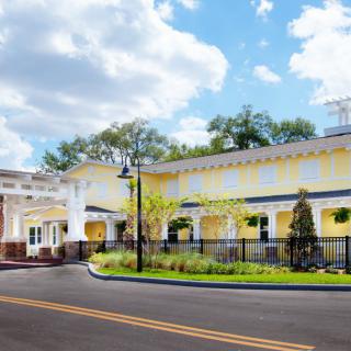 A sunny view of a charming yellow building with a landscaped front yard.