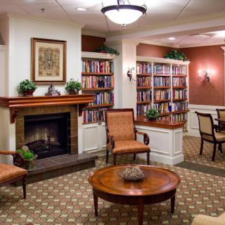 A cozy living room featuring a fireplace, bookshelves filled with books, and comfortable seating.