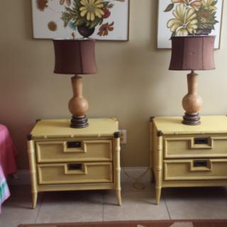 A pair of vintage-style nightstands with matching lamps, set against a backdrop of floral artwork.