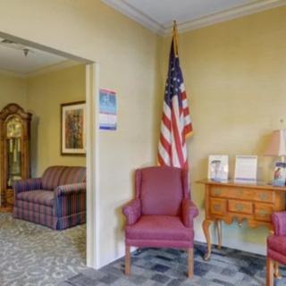 A cozy waiting room with red chairs, an American flag, and decorative furnishings.