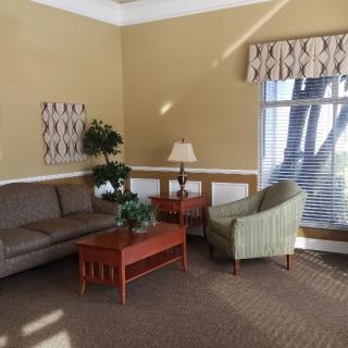 A cozy living room interior with a sofa, armchair, and coffee table by a window.