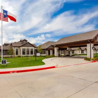 A modern residential building in Texas featuring a flag and a well-maintained driveway under a cloudy sky.