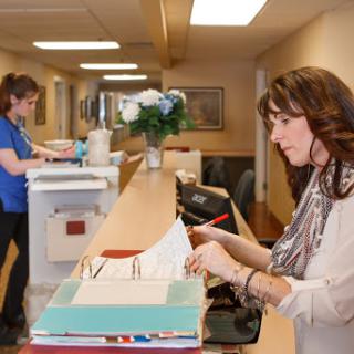 Two staff members working in an office reception area.