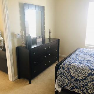 A cozy bedroom with a dresser and mirror beside a bed with patterned bedding.