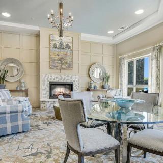 A cozy living room with elegant furnishings, featuring a fireplace and a chandelier.