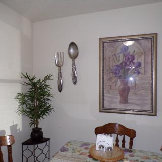 A cozy dining area with large utensils and floral artwork on the wall.