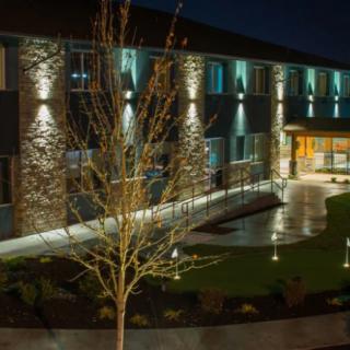 A modern building illuminated at night with landscaped surroundings.