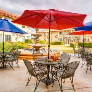 A picturesque patio with colorful umbrellas, tables, and chairs surrounding a central fountain.