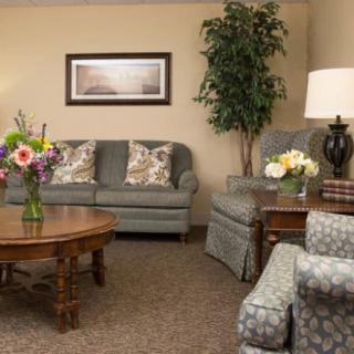 A cozy living room with a sofa, coffee table, and decorative plants and flowers.