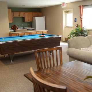 A cozy lounge area featuring a billiards table, kitchen, and comfortable seating.