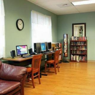 A cozy computer room with several computers, bookshelves, and comfortable seating.