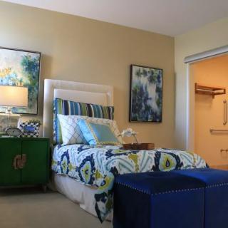 A stylishly decorated bedroom featuring a bed with patterned bedding, vibrant artwork, and modern furnishings.