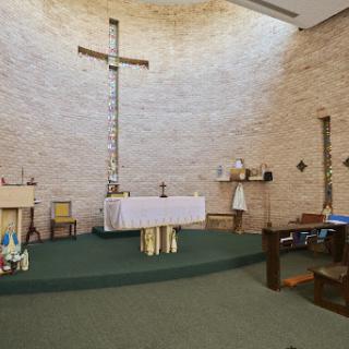 A serene view of a church altar with a prominent cross and minimalist decor.