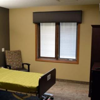 A minimalist hospital room with a bed, chair, and window.