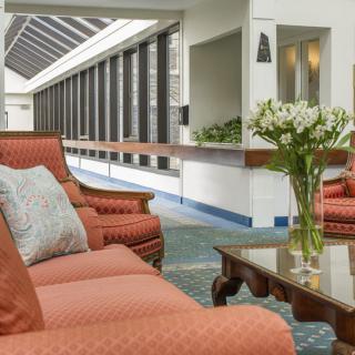 A modern lobby area featuring comfortable sofas, a coffee table, and a vase of flowers.