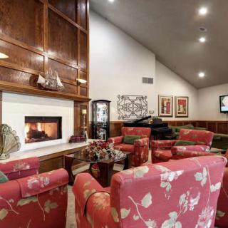 A cozy living room featuring a fireplace, floral armchairs, and elegant wood paneling.