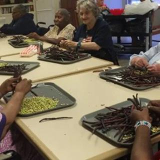 A group of seniors engaged in an indoor crafting activity at a community center.