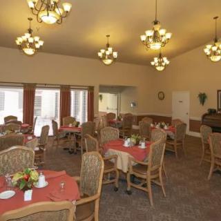 An elegant dining area with neatly arranged tables and chairs, illuminated by chandeliers.