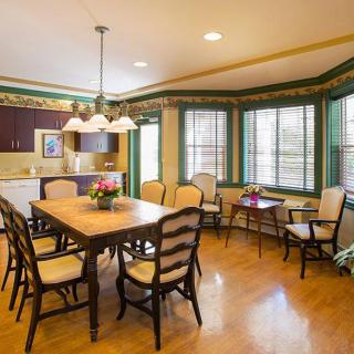 A bright dining room with a wooden table and chairs, featuring large windows and modern lighting.